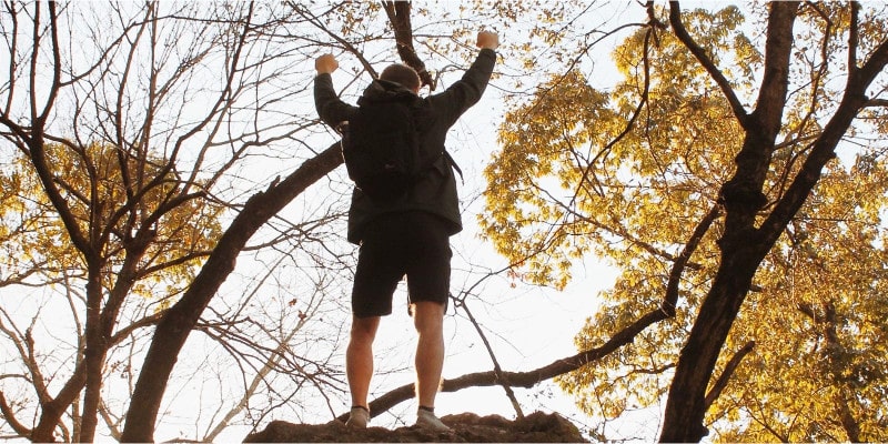 Ein Mann steht auf einem Felsen und macht eine Power-Pose