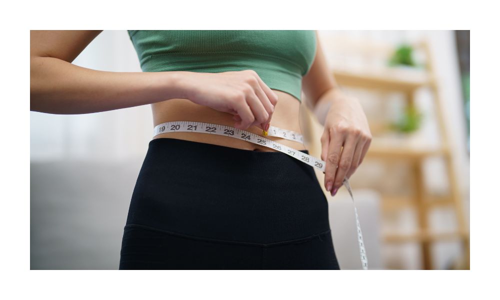 junge Frau im Sportoutfit hält ein Maßband im ihre Taille, Beitragsbild zum Blogartikel in der Kategorie Aquafitness, Kalorienverbrauch im Vergleich